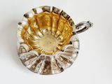 a silver bowl with a handle on a white surface