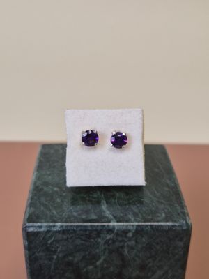 une paire de boucles d'oreilles en saphir violet posées sur un bloc de marbre