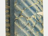 un vieux livre posé sur une table blanche à côté d'un mur blanc