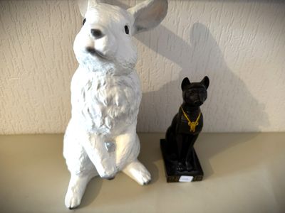 une statue représentant une souris et un chat noir posée sur une étagère