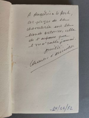 un livre ouvert, sur lequel est inscrit un poème manuscrit, posé sur une table