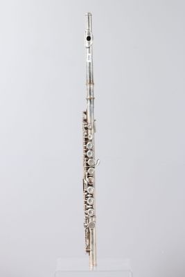 a silver flute on a clear stand against a white background
