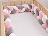 a crib with a pink, white and grey blanket on it