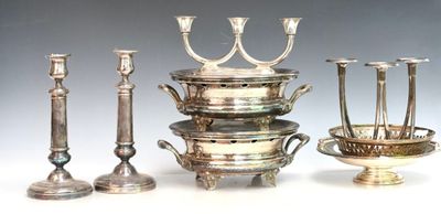 quatre chandeliers en argent et un bol posés sur une table