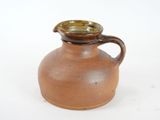 a brown vase with a brown handle on a white surface
