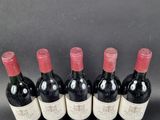 six bottles of red wine lined up in a row on a table