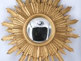 an image of a gold sunburst mirror on a white wall