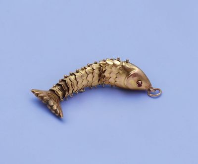 an image of a gold plated fish charm on a blue background