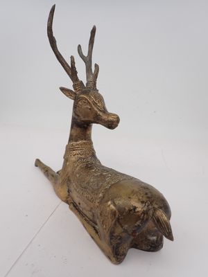 sculpture en bronze représentant un cerf couché sur une surface blanche