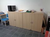 a room with a desk, cabinets, and a television