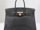 un sac à main en cuir noir muni d'un fermoir doré sur la poignée