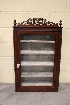 une vieille vitrine en bois avec des portes vitrées, posée sur le trottoir