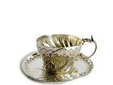 une tasse à thé en argent et sa soucoupe, posées sur une soucoupe