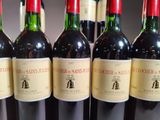 six bottles of red wine are lined up on a table