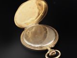 a close up of a gold pocket watch on a black surface