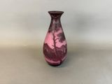 a purple vase sitting on a table with a white wall in the background
