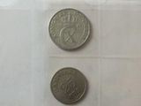 two coins are shown in a clear plastic container on a white surface