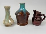 trois vases posés l'un à côté de l'autre sur une surface blanche