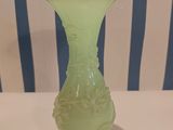 a green vase with a gold rim on a white table