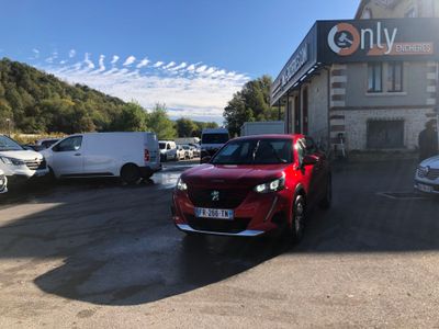 La voiture rouge est garée devant l'immeuble, sur le parking.