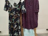 two dresses hanging on a rack in a room