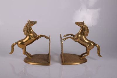 une paire de serre-livres en forme de chevaux dorés sur fond blanc