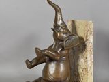 statue of an elephant sitting on a bookend with its trunk in the shape of an elephant