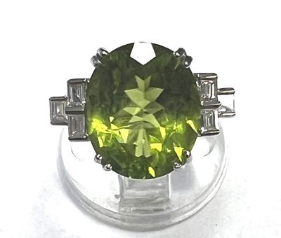 une image d'une bague avec une pierre verte entourée de diamants