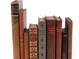 several old books are stacked on top of each other on a white surface