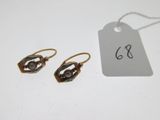 deux paires de boucles d'oreilles et une étiquette posées sur une table blanche