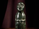 une figurine en pierre verte posée sur une table en bois