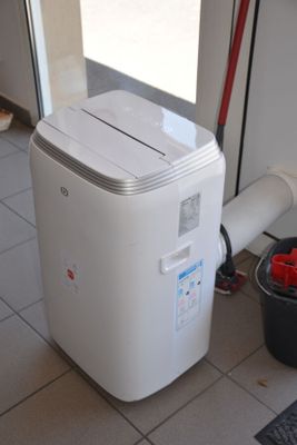 a white air conditioner sitting on the floor next to a window