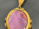 a close up of a gold locke with a purple glass in it