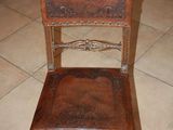 a wooden chair with a leather seat on a tile floor