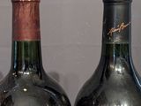 two bottles of wine sitting on a shelf next to each other