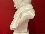 white marble bust of a man in a suit on a red surface