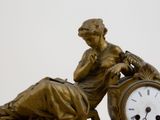 a bronze statue of a woman sitting on a clock