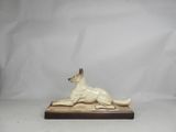 an image of a statue of a dog laying down on a wooden base