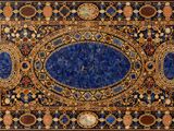 a close up of a blue and gold rug on a white surface