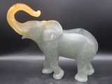 a glass elephant that is standing on a black surface