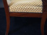 a close up of a wooden chair with a yellow and white upholstered seat