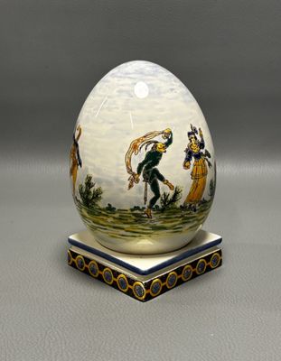un œuf décoré d'une peinture, posé sur un socle
