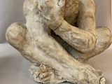 a sculpture of a man sitting on a piece of wood