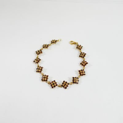 un bracelet en or orné de perles marron sur un fond blanc