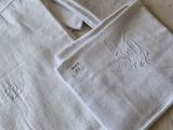trois serviettes blanches ornées de monogrammes brodés, posées sur un lit