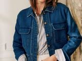 the woman is wearing a denim jacket and white pants