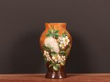 un vase avec des fleurs peintes dessus, posé sur une table