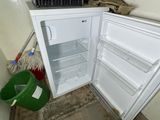 a small white refrigerator in the corner of a room