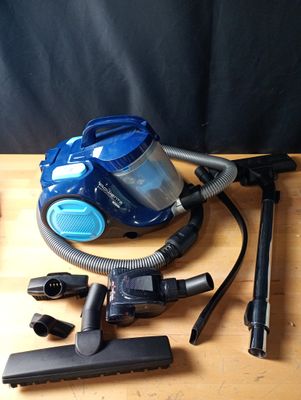 un aspirateur bleu posé sur une table en bois