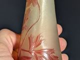 a hand holding a glass bottle with a flower design on it